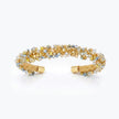 Gold cuff bracelet displaying a handknitted wire band accented with clear and champagne premium crystals.