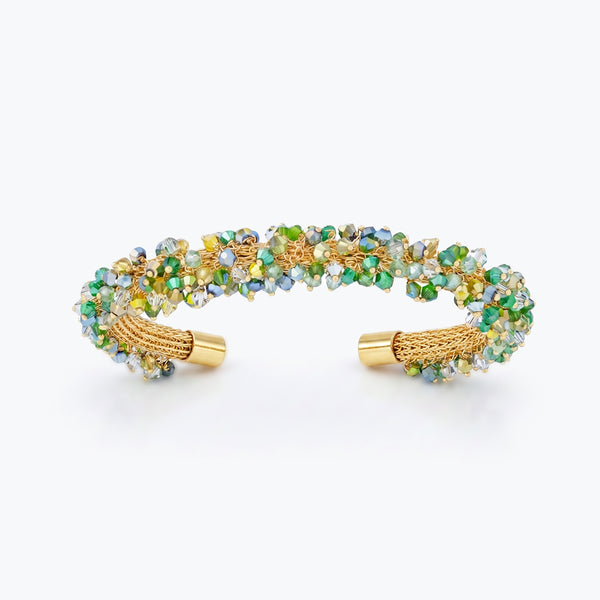 Gold cuff bracelet featuring a handknitted wire mesh design studded with emerald green premium crystals.