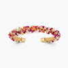 Gold cuff bracelet showing a handknitted wire mesh structure lined with red and pink premium crystals.