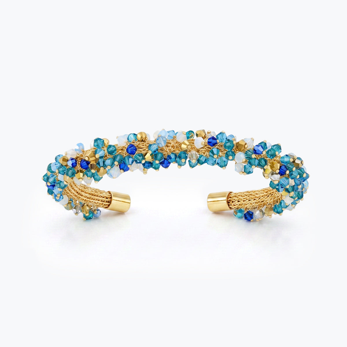 Gold cuff bracelet featuring a handknitted wire mesh band set with blue and aqua reflective crystals.