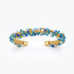 Gold cuff bracelet featuring a handknitted wire mesh band set with blue and aqua reflective crystals.