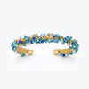 Gold cuff bracelet featuring a handknitted wire mesh band set with blue and aqua reflective crystals.