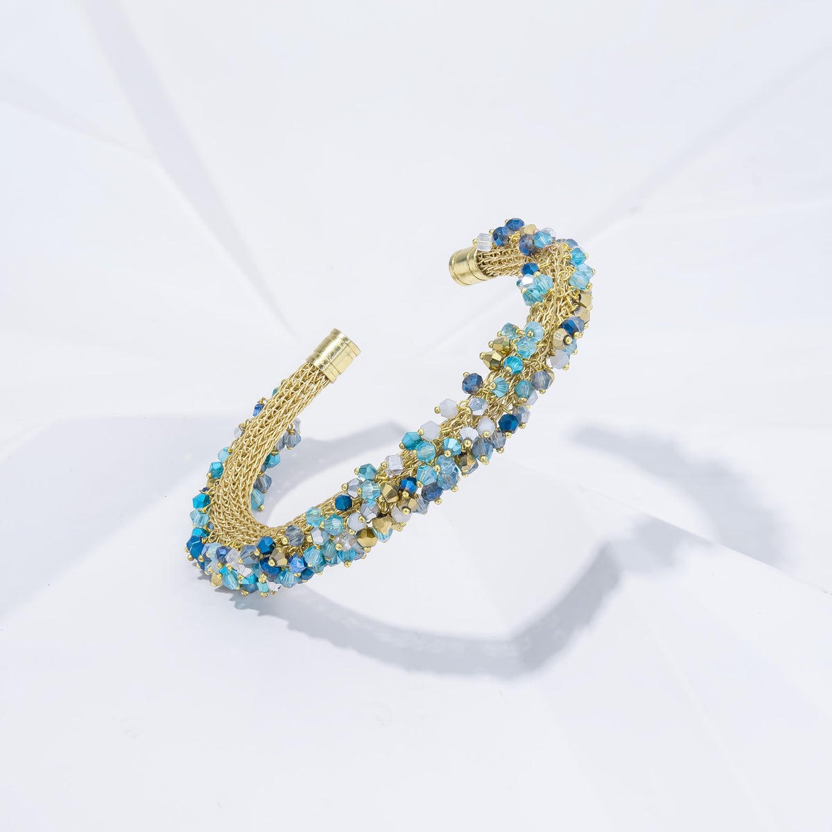 Gold bracelet with blue stones on a white background