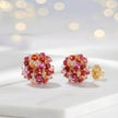 Gold cluster stud earrings with individually hanging crystals in shades of red and pink.