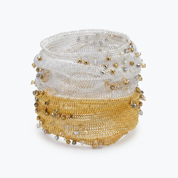 Silver gold distorted cuff bracelet featuring a slender handknitted wire mesh embedded with clear and champagne premium crystals.