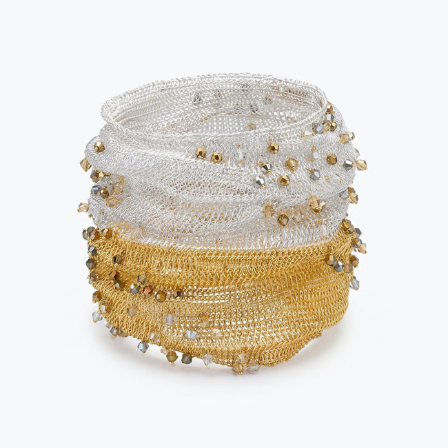 Silver gold distorted cuff bracelet featuring a slender handknitted wire mesh embedded with clear and champagne premium crystals.