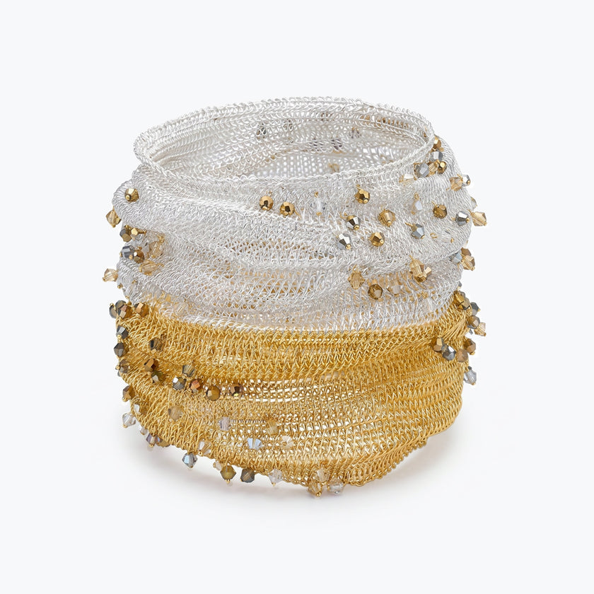 Silver gold distorted cuff bracelet featuring a slender handknitted wire mesh embedded with clear and champagne premium crystals.