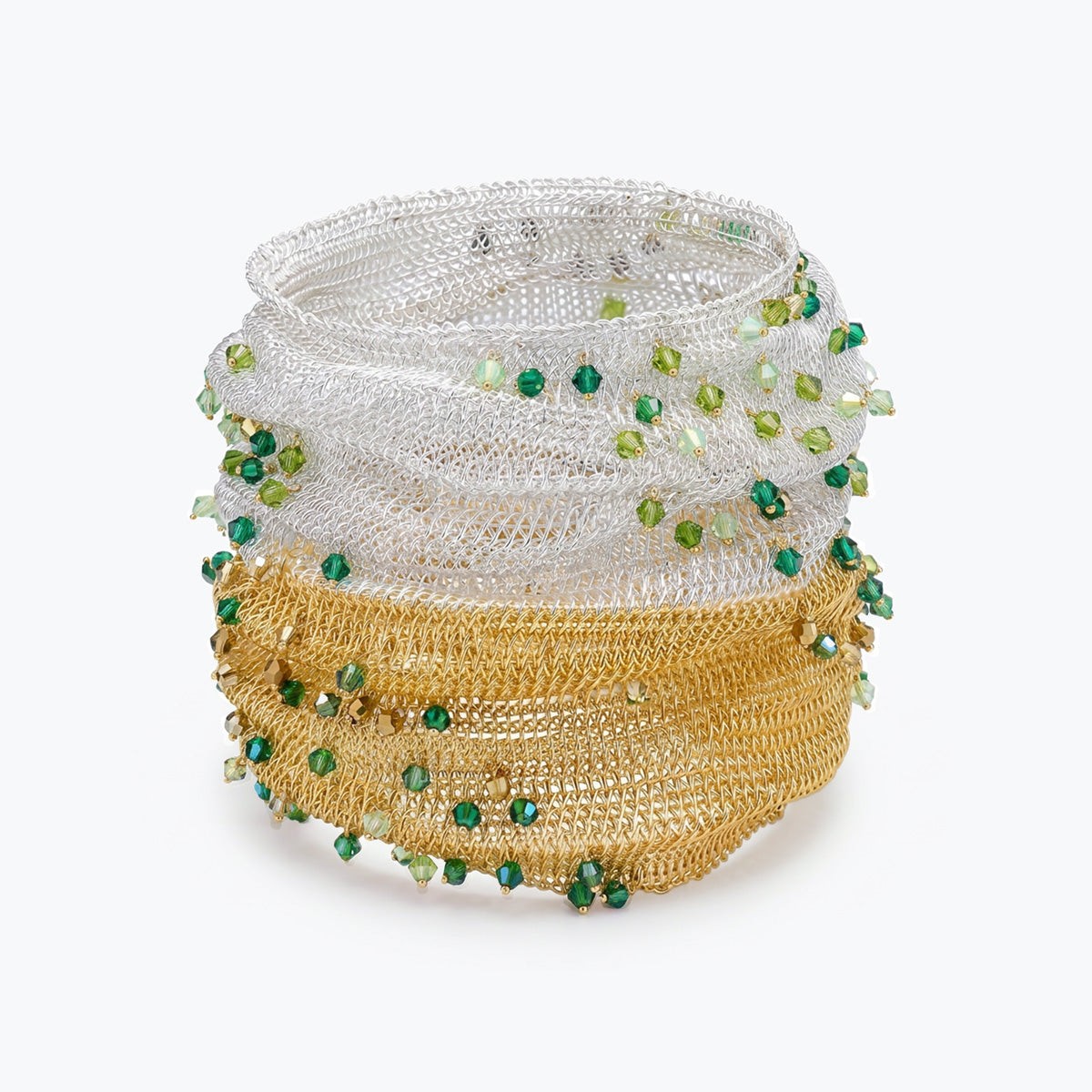 Silver gold distorted cuff bracelet displaying a fit handknitted wire design highlighted by individually hanging green crystals.