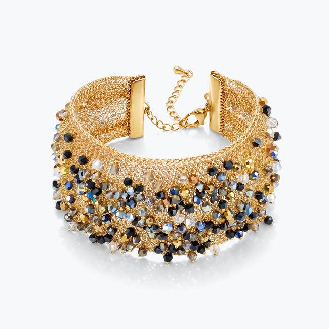Gold cuff bracelet with a textured handknitted wire mesh base holding metallic black, bronze, and silver crystals.