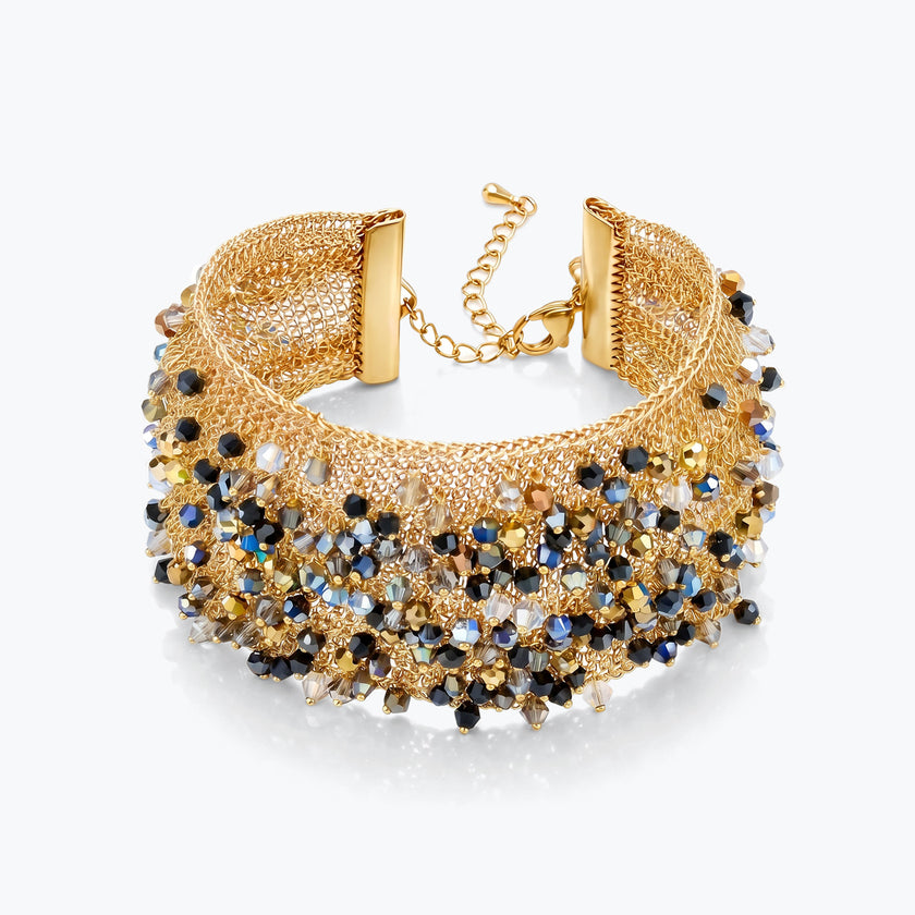 Gold cuff bracelet with a textured handknitted wire mesh base holding metallic black, bronze, and silver crystals.