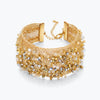 Gold cuff bracelet displaying a textured handknitted wire mesh band with clear and champagne reflective crystals.