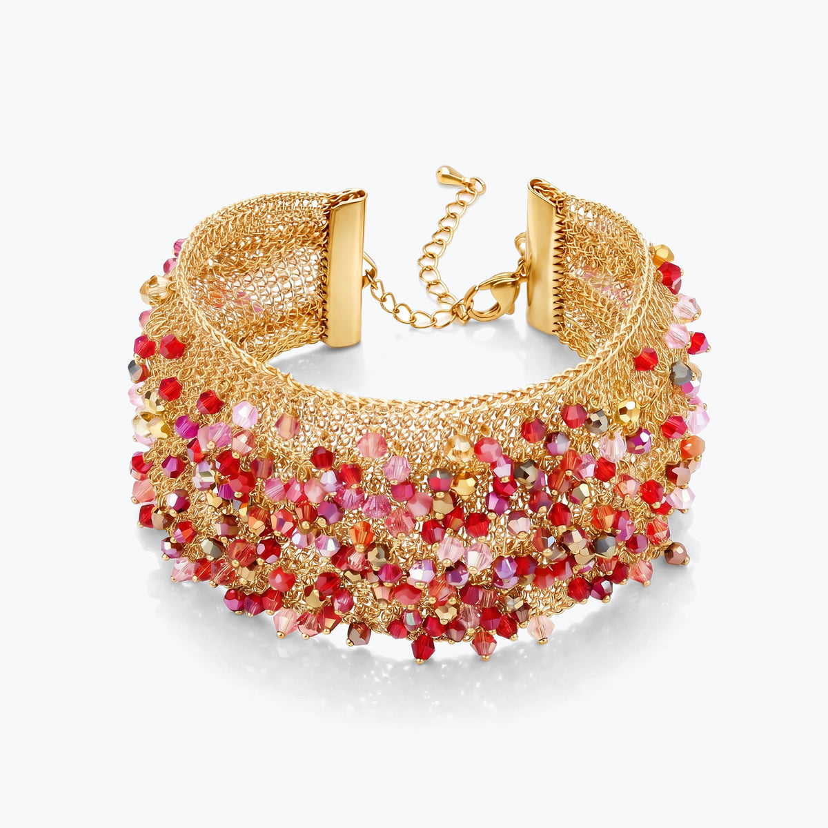 Gold cuff bracelet showing a textured handknitted wire structure finished with rows of red and pink premium crystals.