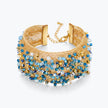 Gold cuff bracelet featuring a woven textured handknitted wire pattern accented by blue and aqua premium crystals.
