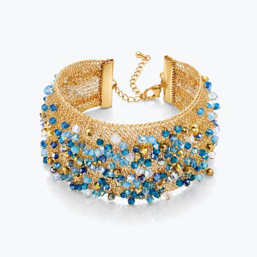 Gold cuff bracelet featuring a woven textured handknitted wire pattern accented by blue and aqua premium crystals.