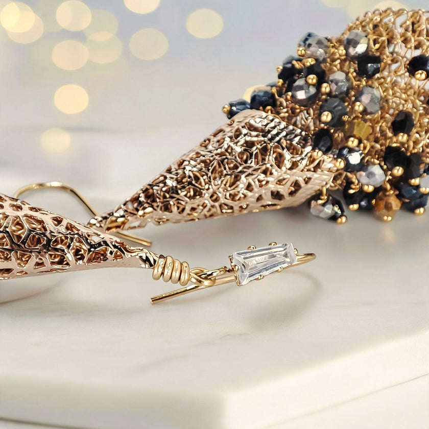 Gold drop earrings composed of handknitted wire cone and individually hanging gunmetal, bronze, and black premium crystals.