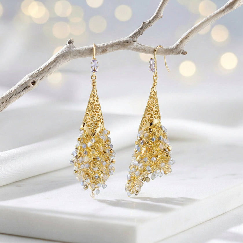 Gold drop earrings with a handknitted wire cone and a cascade of individually hanging champagne, gold and silver reflective crystals.