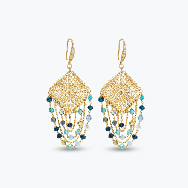Gold drop earrings with a diamond-shaped handknitted wire mesh square panel and cascading strands of blue reflective crystals.
