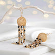 Gold drop earrings featuring a sphere-shaped handknitted wire shape and tassel strands of black and bronze crystals.