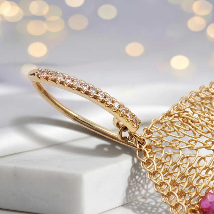 Gold drop earrings showcasing a handknitted wire rhombus panel housing bright pink and red reflective crystals.