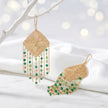 Gold drop earrings with a handknitted wire rhombus panel and layered green and emerald individually hanging crystals.
