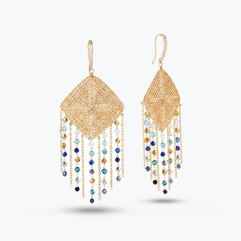 Gold drop earrings featuring a handknitted wire mesh rhombus panel frame and cascading blue and gray reflective crystals.