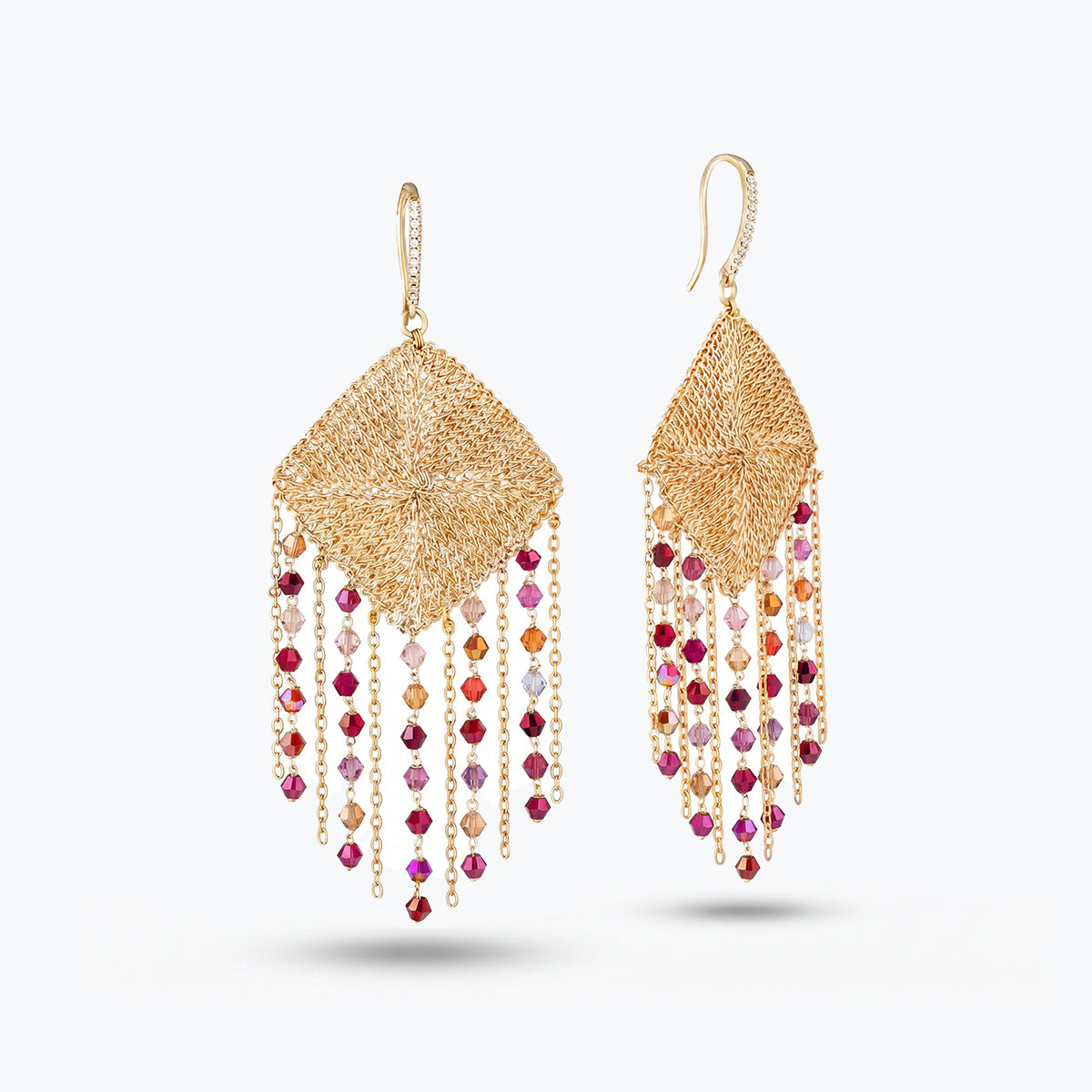Gold drop earrings showcasing a handknitted wire rhombus panel housing bright pink and red reflective crystals.