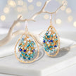 Gold drop earrings featuring a  handknitted wire mesh teardrop shape with dangling blue and silver premium crystals.