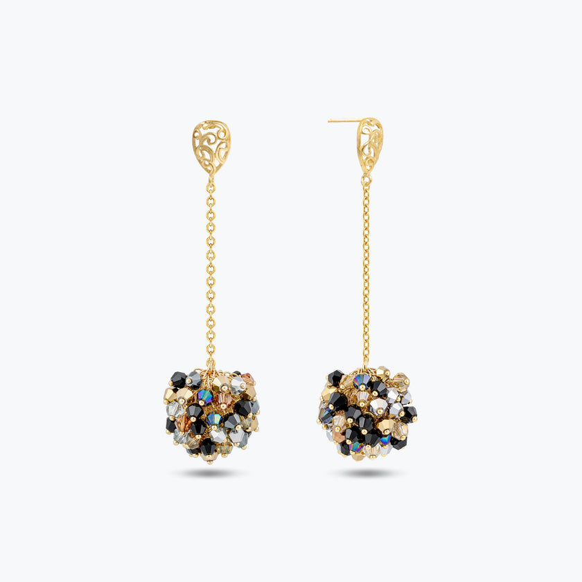 Gold drop earrings featuring a handknitted wire mesh ball with hanging bronze, gray, and black premium crystals.
