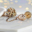 Gold drop earrings displaying a  handknitted wire mesh ball and clusters of clear and gold premium crystals.
