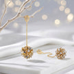 Gold drop earrings displaying a  handknitted wire mesh ball and clusters of clear and gold premium crystals.
