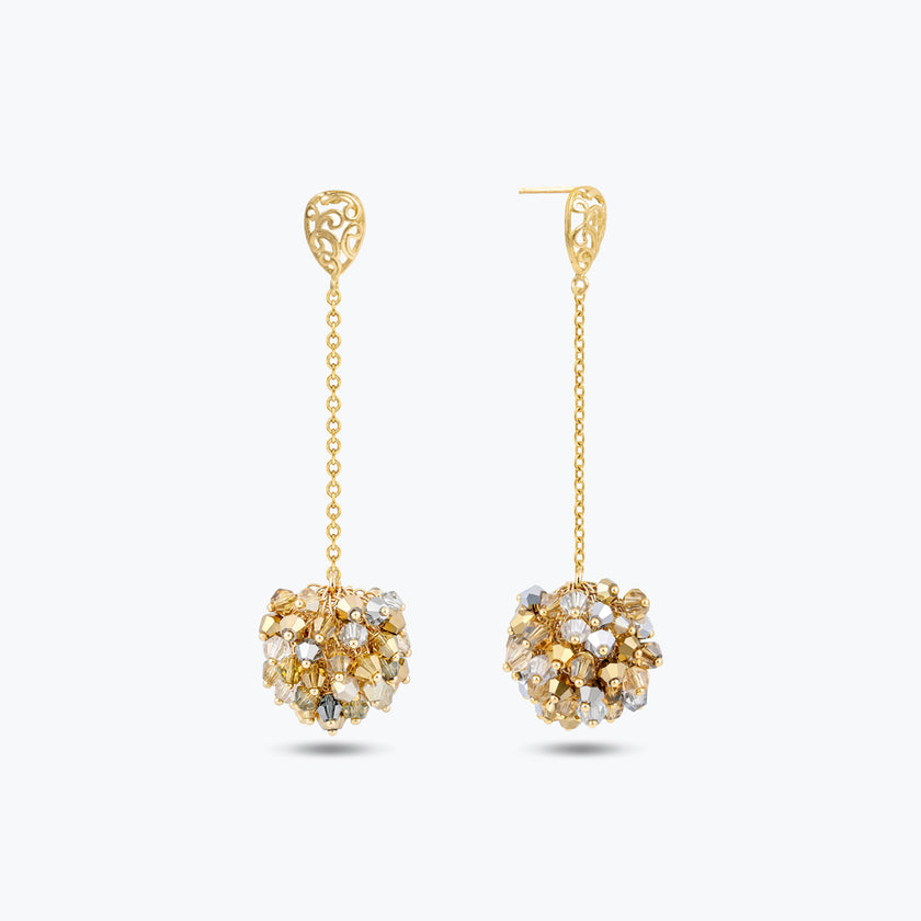 Gold drop earrings displaying a  handknitted wire mesh ball and clusters of clear and gold premium crystals.
