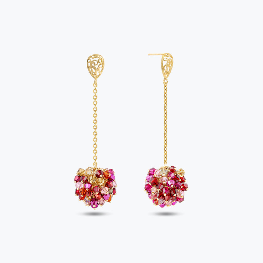 Gold drop earrings showcasing a handknitted wire mesh ball  filled with hanging pink and red crystals.
