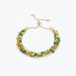 Gold handknitted wire slider bracelet displaying green, emerald, mint, and gold premium crystals.