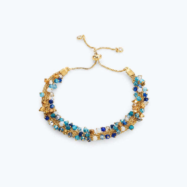 Gold handknitted wire slider bracelet featuring blue, turquoise, aqua, and bronze premium crystals.