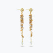Gold drop earrings featuring a long linear handknitted wire design with hanging champagne and clear premium crystals.
