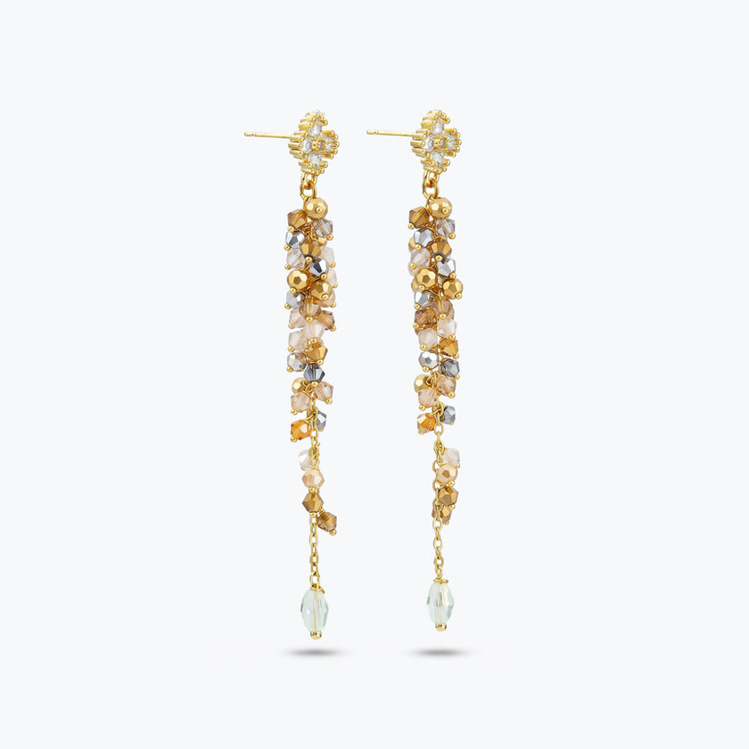 Gold drop earrings featuring a long linear handknitted wire design with hanging champagne and clear premium crystals.

