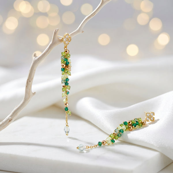 Gold drop earrings with a vertical handknitted wire mesh strip trailing down into green individually hanging crystals.
