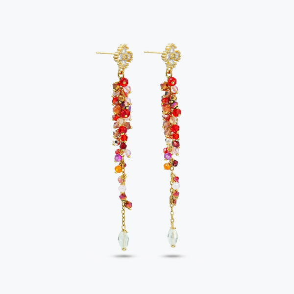 Gold drop earrings featuring an elongated handknitted wire mesh bar holding individually hanging pink and red crystals.
