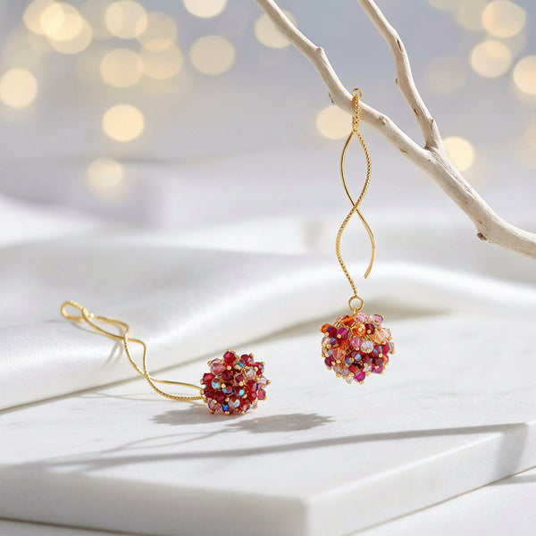 Gold spiral drop earrings with a rounded bunch of premium crystals in red, pink, and orange tones.