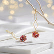 Gold spiral drop earrings with a rounded bunch of premium crystals in red, pink, and orange tones.