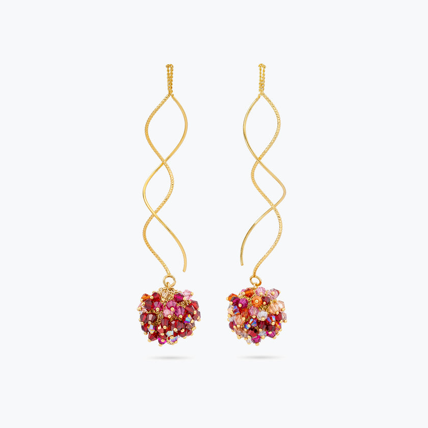 Gold spiral drop earrings with a rounded bunch of premium crystals in red, pink, and orange tones.