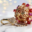 Long gold drop earrings featuring a handknitted wire mesh pod tightly packed with red and pink premium crystals.