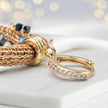 Gold loop earrings featuring a crescent handknitted wire outline and individually hanging black and bronze crystals.