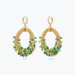 Gold loop earrings displaying a curved crescent handknitted wire mesh frame filled with hanging green premium crystals.