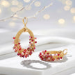 Gold loop earrings showcasing a curved crescent handknitted wire base with cascading red and pink premium crystals.
