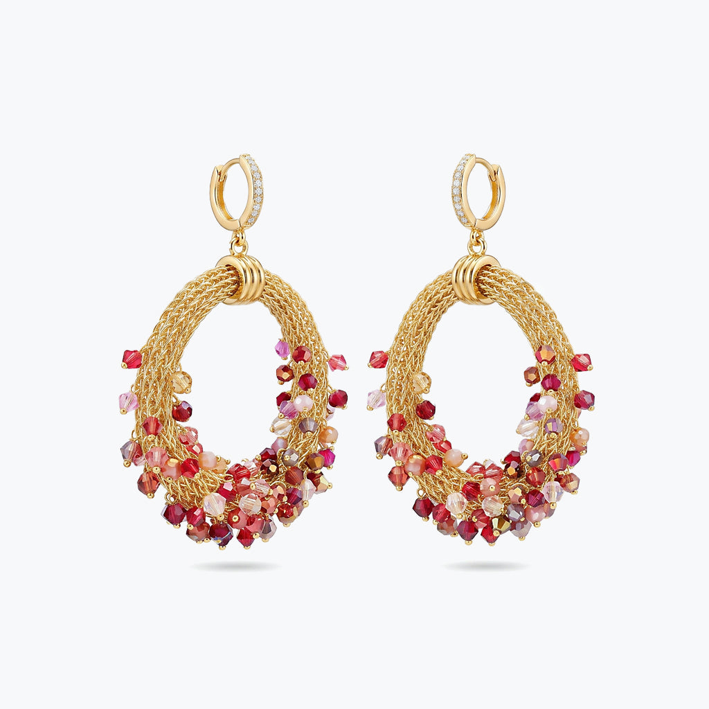 Gold loop earrings showcasing a curved crescent handknitted wire base with cascading red and pink premium crystals.
