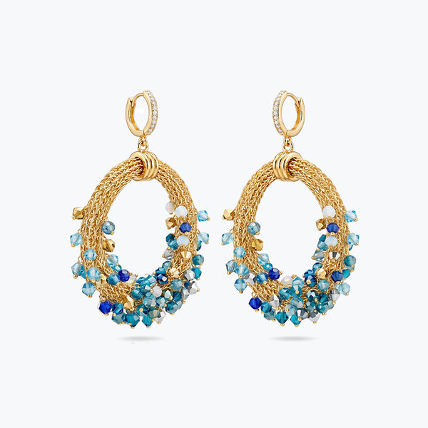 Gold loop earrings featuring a curved crescent handknitted wire mesh base and dangling blue and teal premium crystals.
