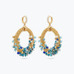 Gold loop earrings featuring a curved crescent handknitted wire mesh base and dangling blue and teal premium crystals.
