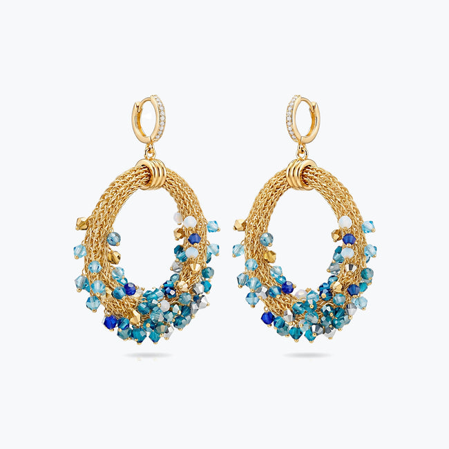 Gold loop earrings featuring a curved crescent handknitted wire mesh base and dangling blue and teal premium crystals.
