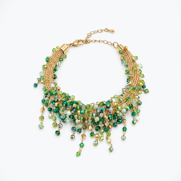 Gold bracelet showing an openwork handknitted wire mesh design highlighted by individually hanging green crystals.
